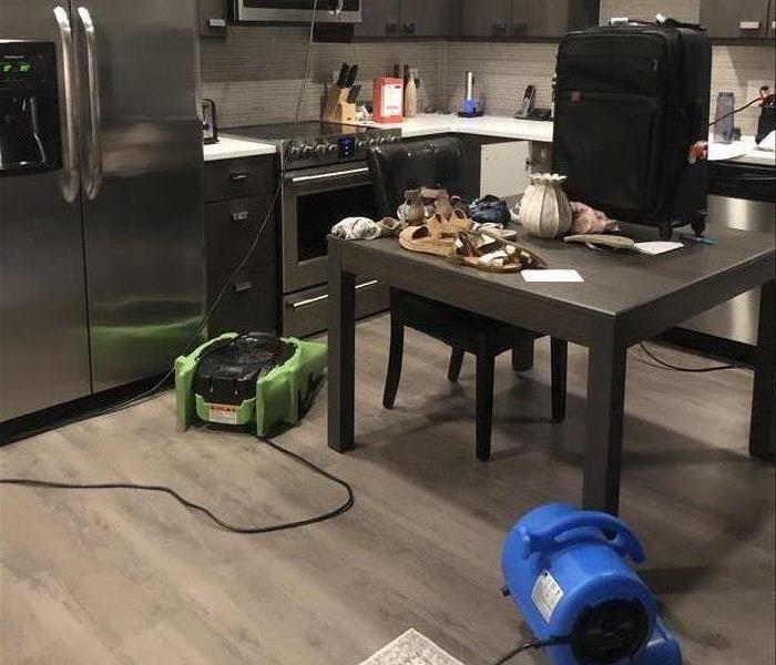 kitchen with stainless steel appliances and one green and blue air movers on the floor.  