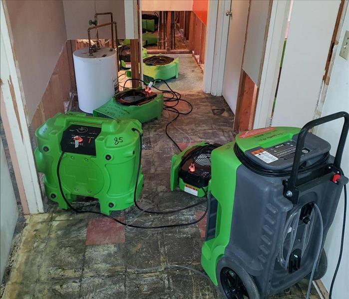 Drying equipment on floor and flood cuts in walls of hallway.