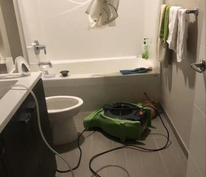 Bathroom with a green air mover in front of the bathtub. 